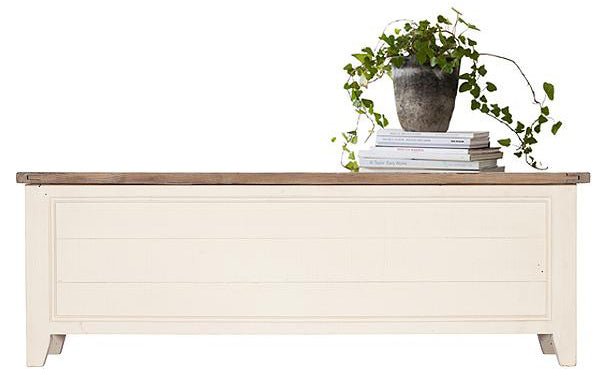 A reclaimed wood blanket box in white paint with a green plant on top