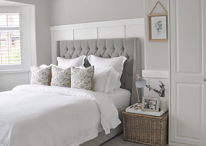 large bed with grey fabric headboard and wicker bedside table