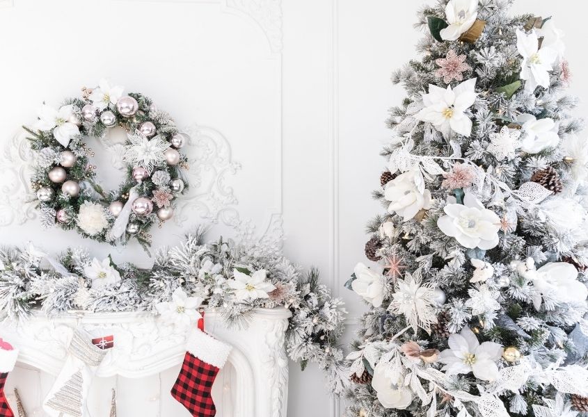 Christmas tree and white mantelpiece decorated in white and pastel decorations.