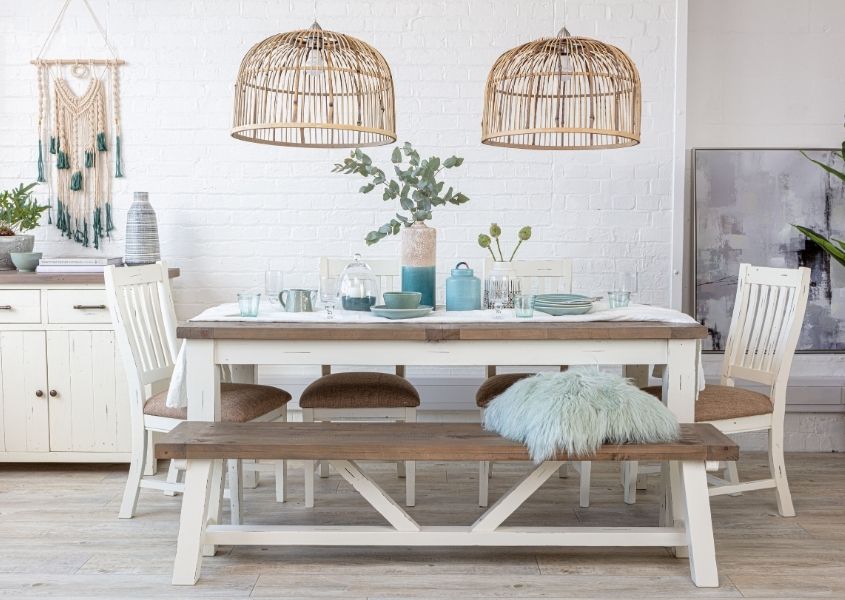 Double bamboo hanging pendant light over a reclaimed wood dining table with white painted legs and matching wooden bench