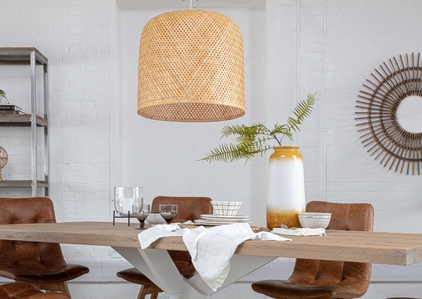 Large bamboo pendant light over large wooden dining table with white spider legs