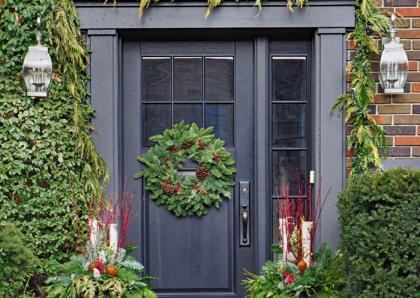 Dark blue front door with round green Christmas wreath and large green bushes