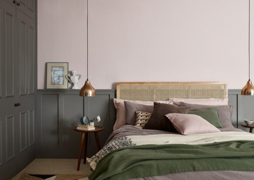 Solid wood bed and wooden bedside table with pale pink walls