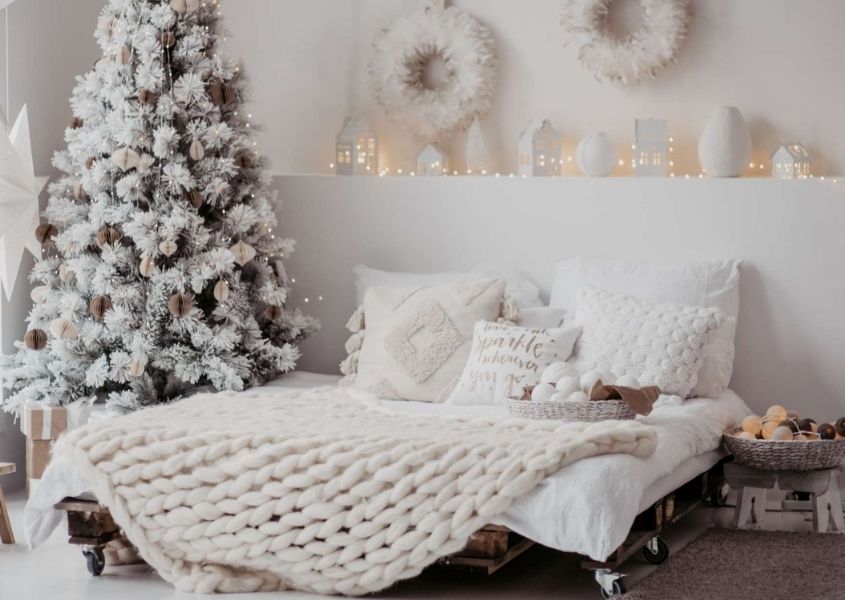 large double bed with white covers and Christmas tree in bedroom