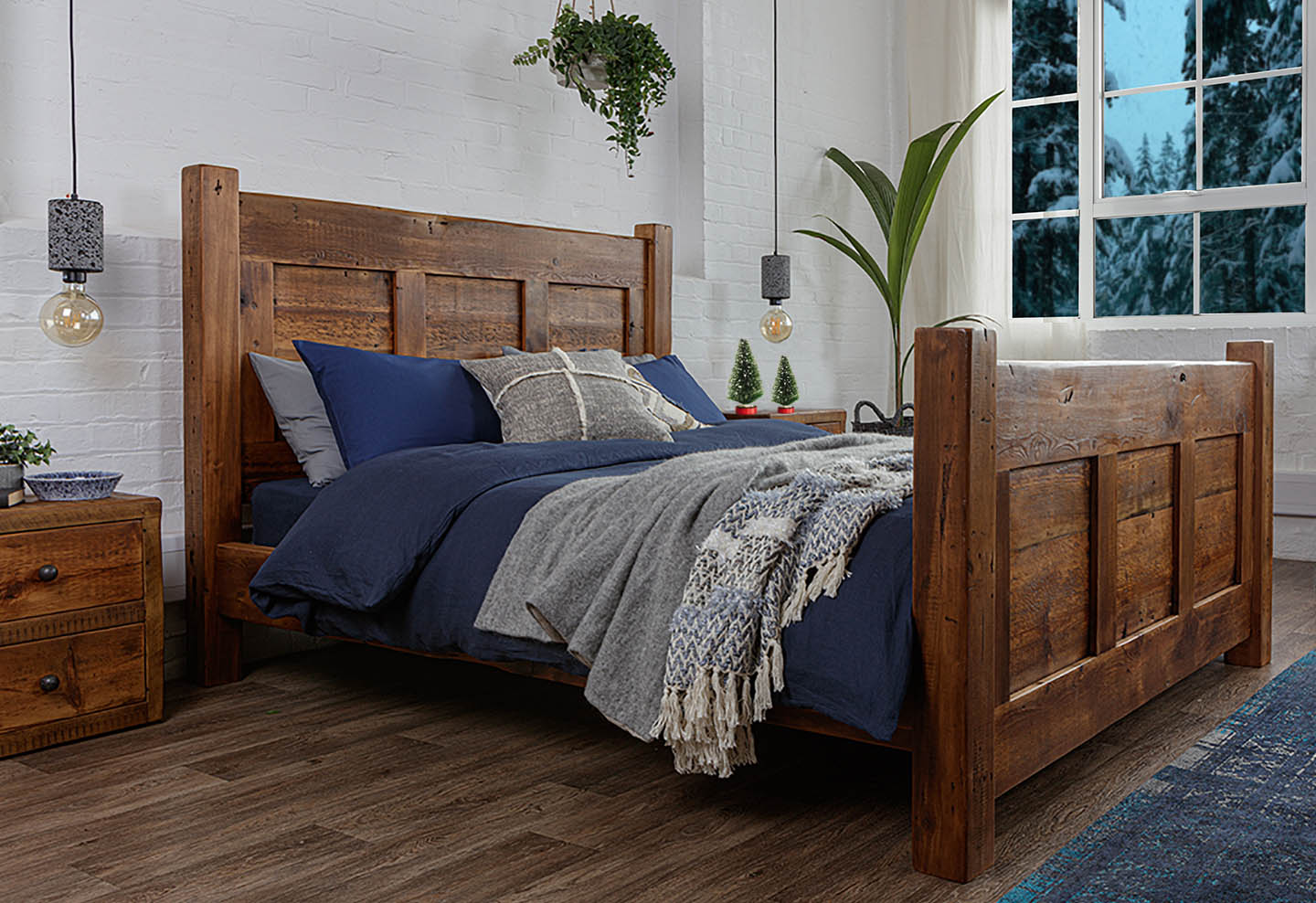 reclaimed wooden bed frame with blue covers and small Christmas trees on bedside table