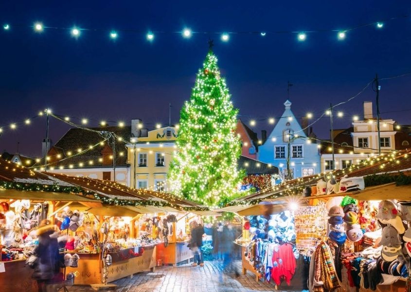 Christmas market scene with large lit up Christmas tree and fairy lights