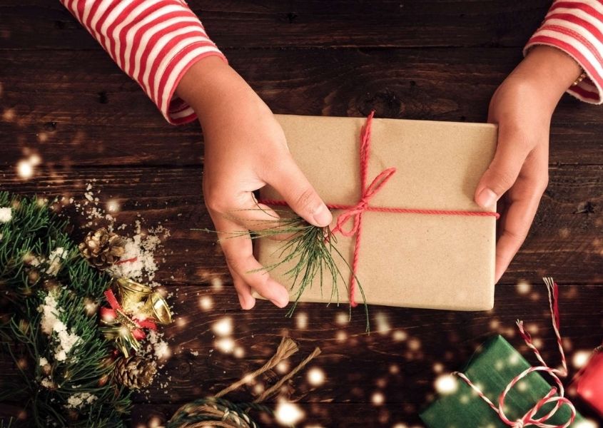 present wrapped in brown paper on wooden dining table