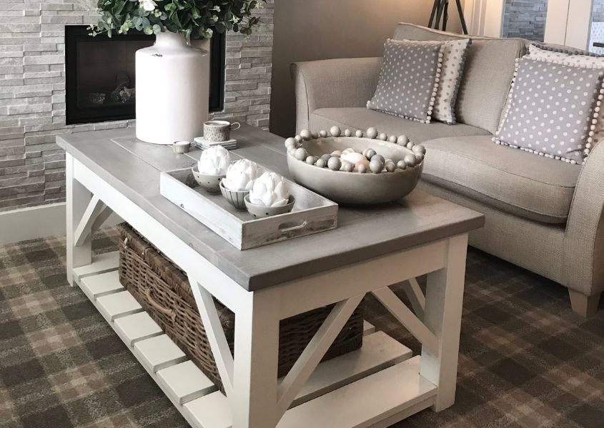 Wooden coffee table with white painted legs and white candle and ornaments on its surface