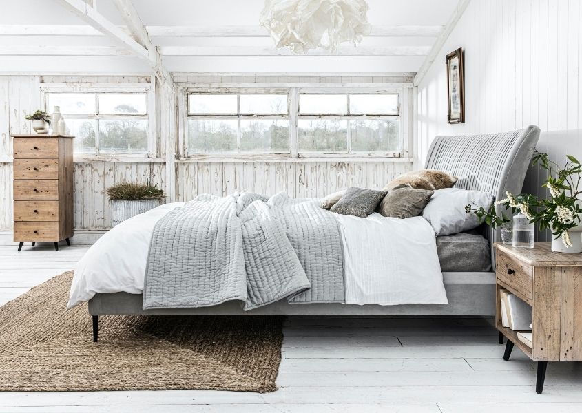 white bedroom with rustic bedroom side table and king size bed with grey cushions