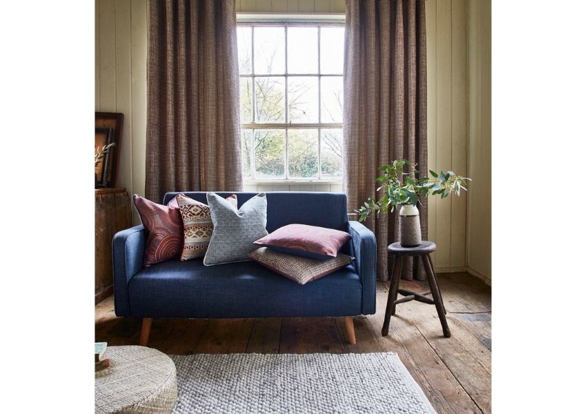 Blue fabric sofa with grey rug and rustic wood side table