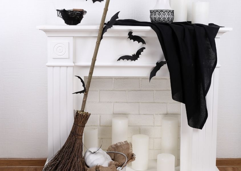white fireplace with broomstick and black Halloween decorations