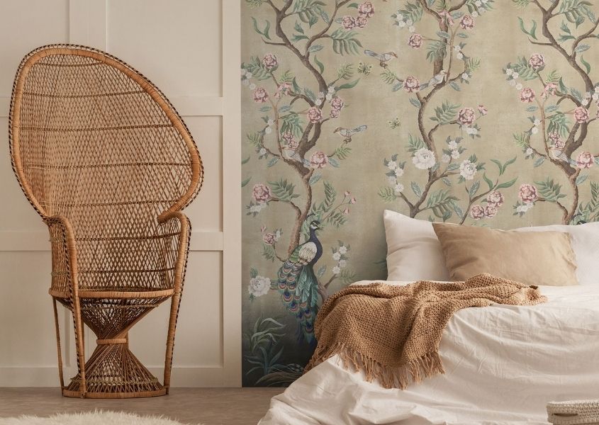 large bamboo armchair and wooden bed with patterned wallpaper