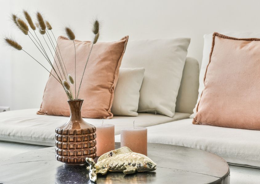 small pots on a wooden coffee table next to white sofa with pink cushions