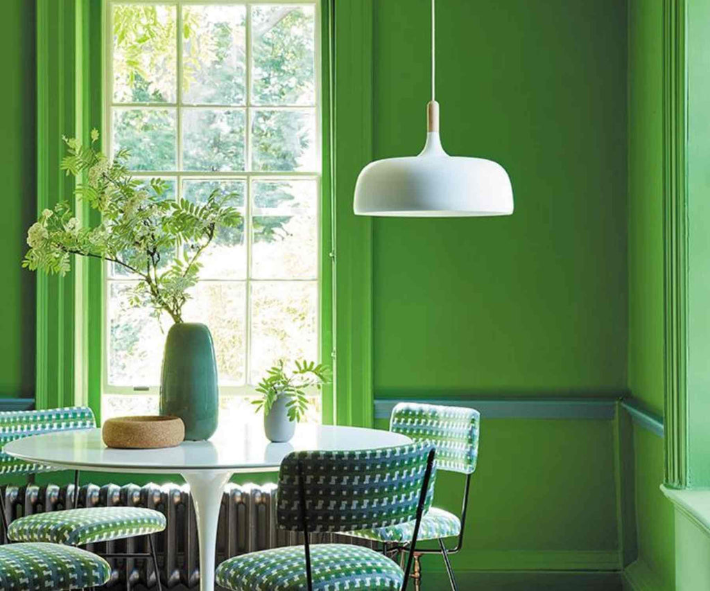 Bright green painted walls with white dining tale and white hanging light