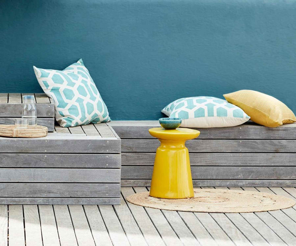 Deep blue outside wall with wooden bench and yellow accesories