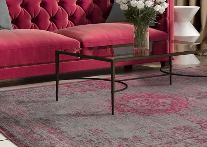 Faded pink rug with glass coffee table and pink velvet sofa