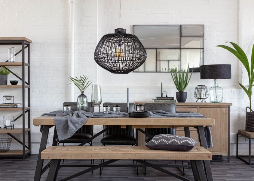Black bamboo hanging light over an industrial dining table with rustic top and black steel frame with matching wooden bench