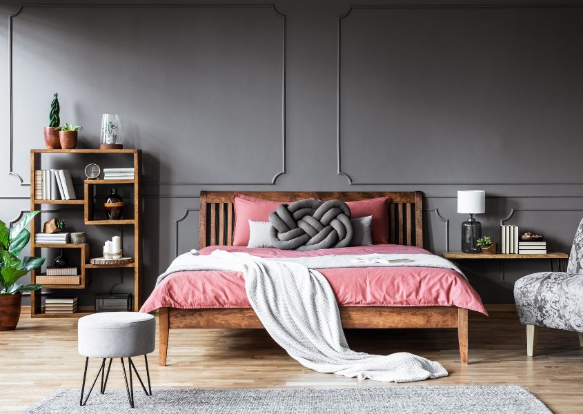 solid wood bed with pink covers in a grey coloured bedroom