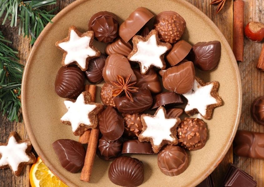 Assortment of milk chocolates and white star biscuits on a brown plate