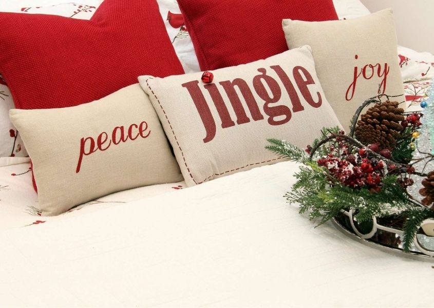 Red and white Christmas cushions on white bed covers