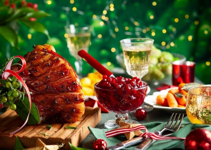 Traditional Christmas dinner on dining table with glazed ham and cranberry sauce in a glass jar