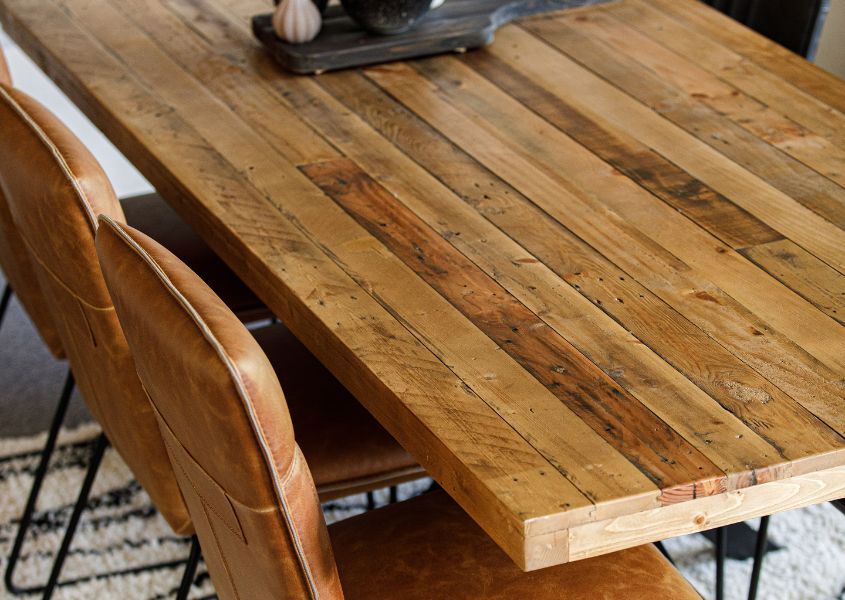 close up of reclaimed wood dining table and brown faux leather dining chairs