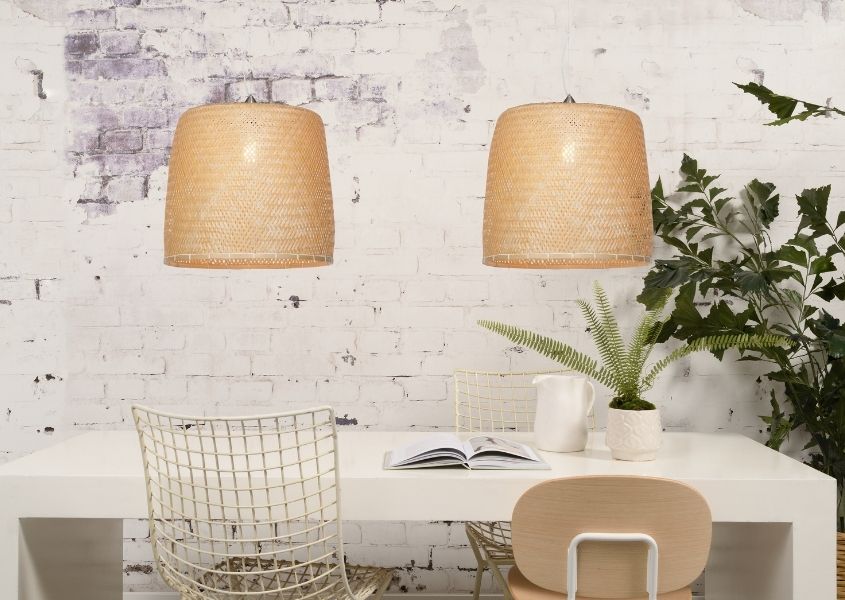 Large bamboo double pendant light over white dining table against white exposed brick wall