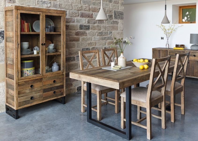 Dining room with reclaimed wood industrial dining table, wooden chairs and rustic glass display cabinet