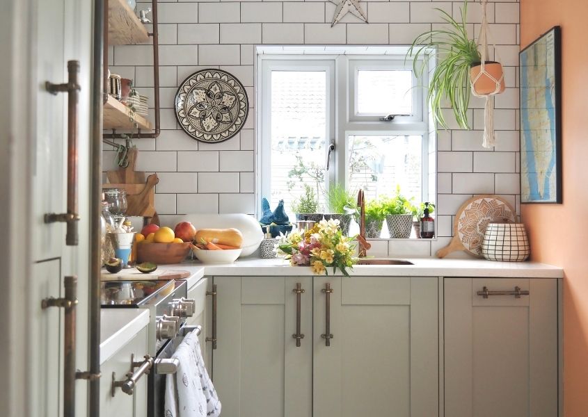 kitchen with grey wooden units and long gold handles with white tiles