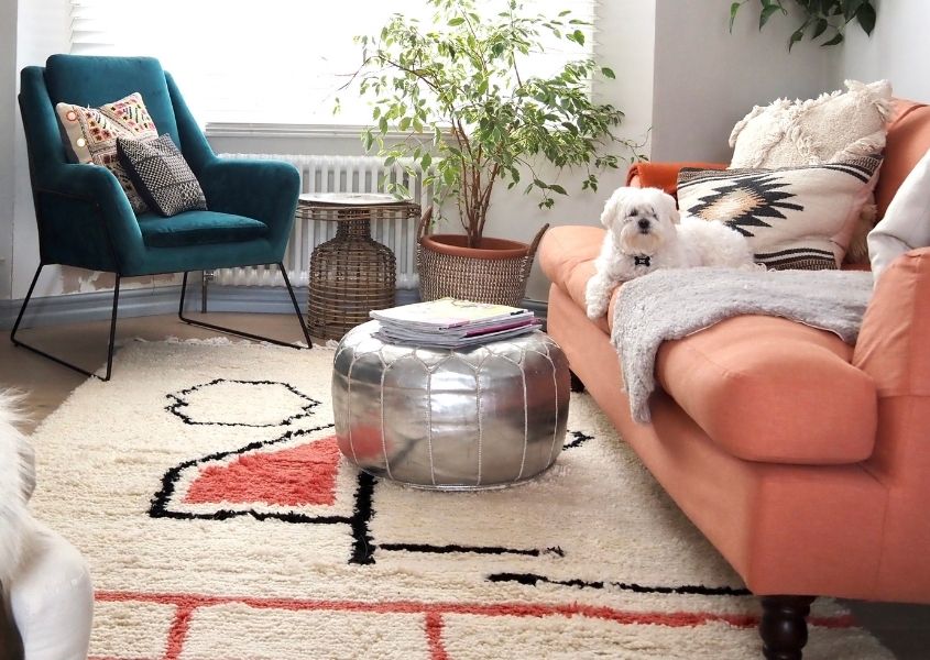 living room with coral fabric sofa, silver pouffe and patterned floor rug