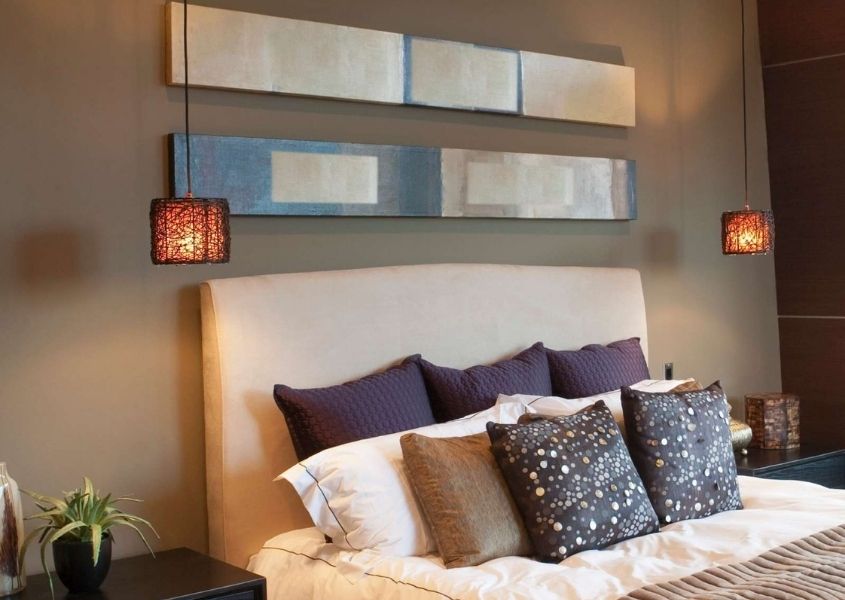 Beige bedroom with padded headboard and two small orange fabric pendant lights beside bed