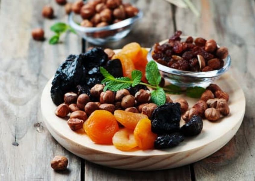Plate of dried fruits and nuts on rustic wood background 