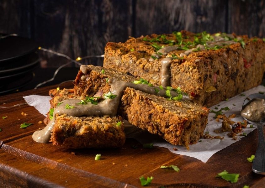 A prepared nut roast with slices cut on brown wooden table