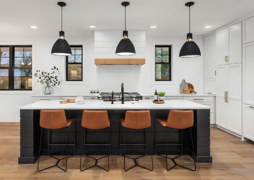 modern farmhouse kitchen with black hanging pendant lights and brown leather bar stools