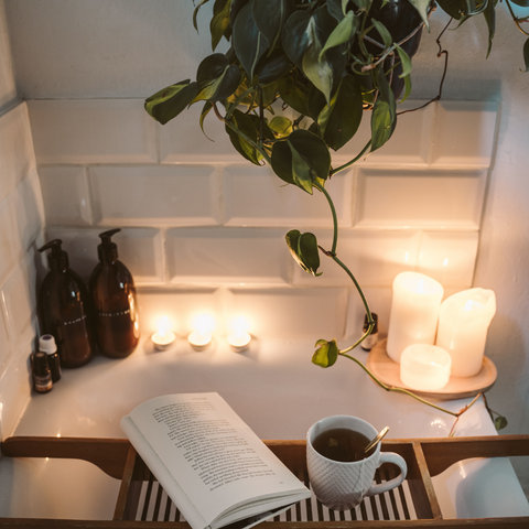 relaxing bath with a book and a cup of chamomile tea. There is candle light. 