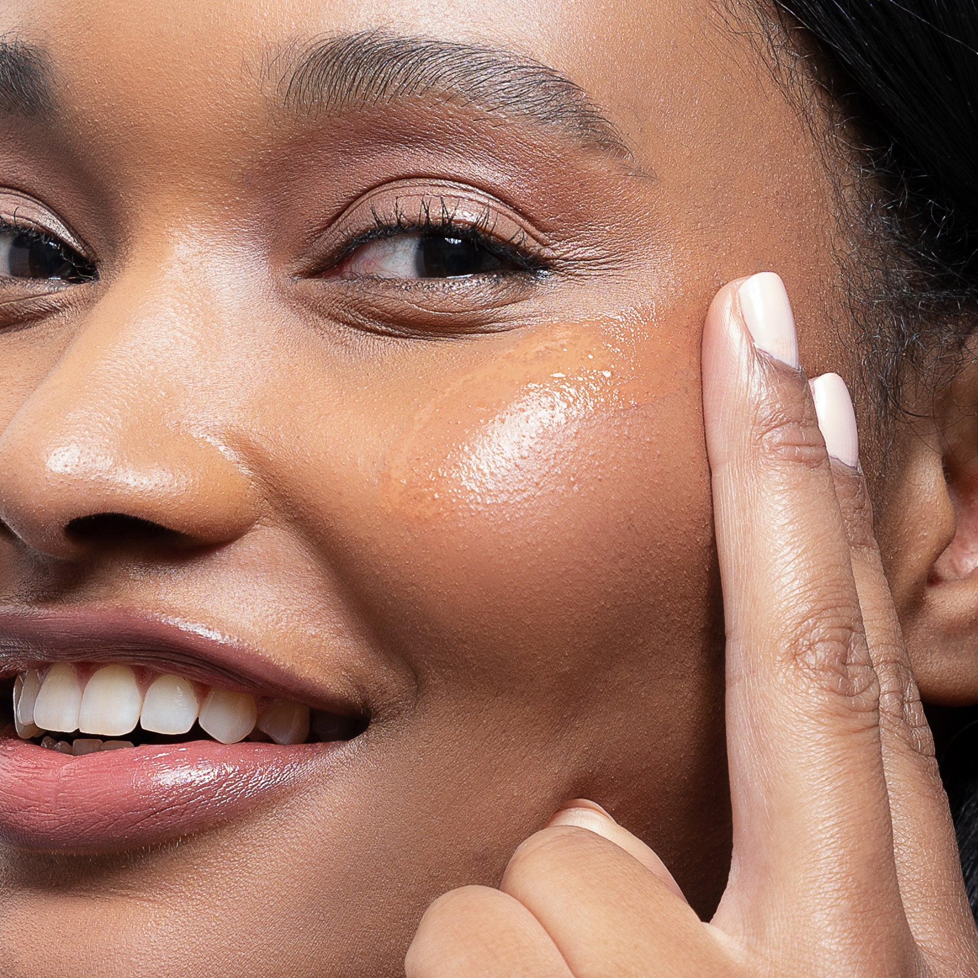 Closeup shot of models face with Beekman 1802 Milk Tint SPF 43 Tinted Primer Serum swatch on her cheek.