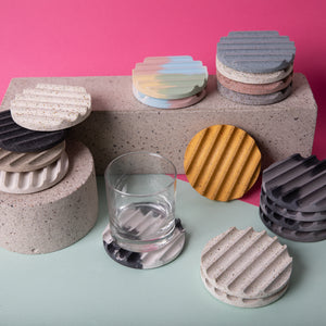 Concrete coasters in black and grey alongside various other colored coasters.
