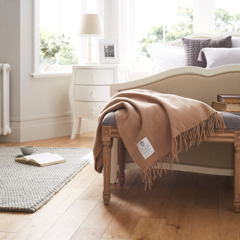 A merino wool throw draped over the end of a bed frame