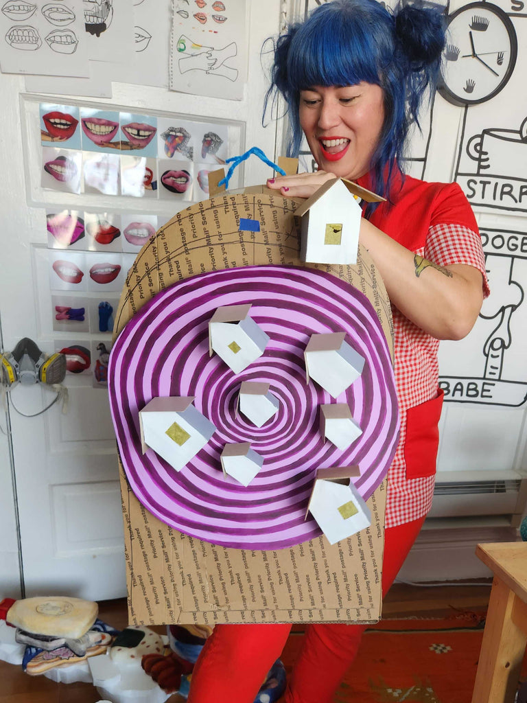 Risa with a cardboard paper creation of a wheel with houses