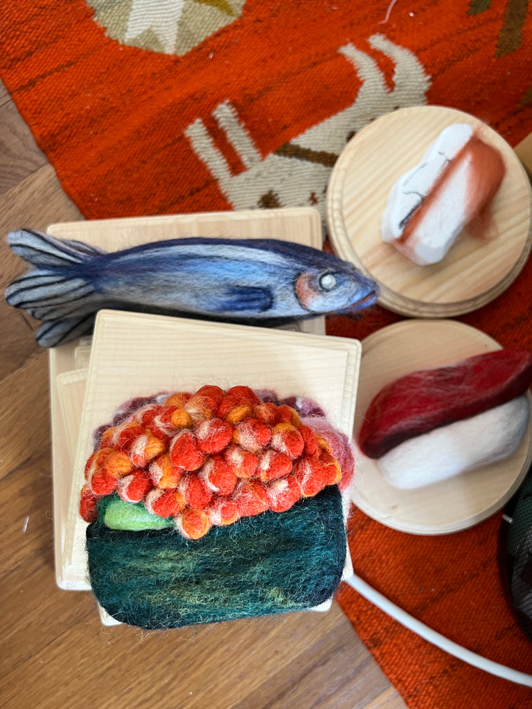 Felted food pieces; a mackerel, a ikura sushi and a tuna nigiri.