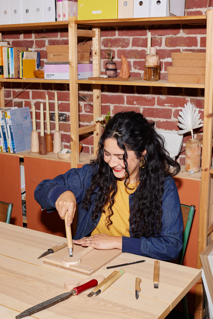 Artist Melanie Abrantes carving a wooden panel