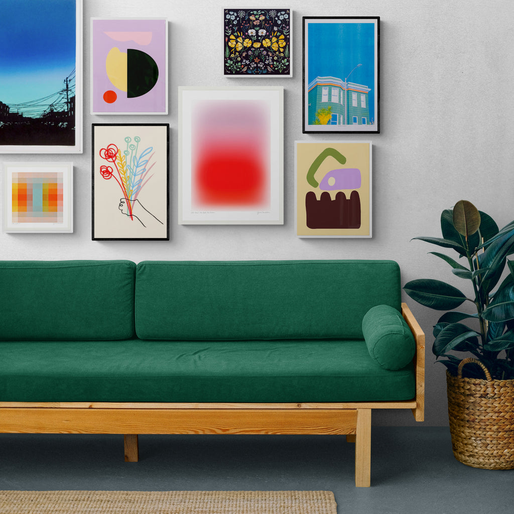 A green couch with a salon-style gallery wall of artwork above it consisting of abstract color art and still life