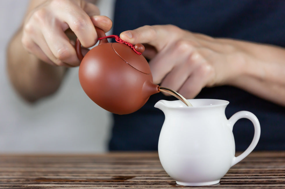 tea pot pouring tea into pitcher