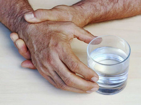 Close-up of a hand with a tremor struggling to hold a spoon, highlighting essential tremor treatments.