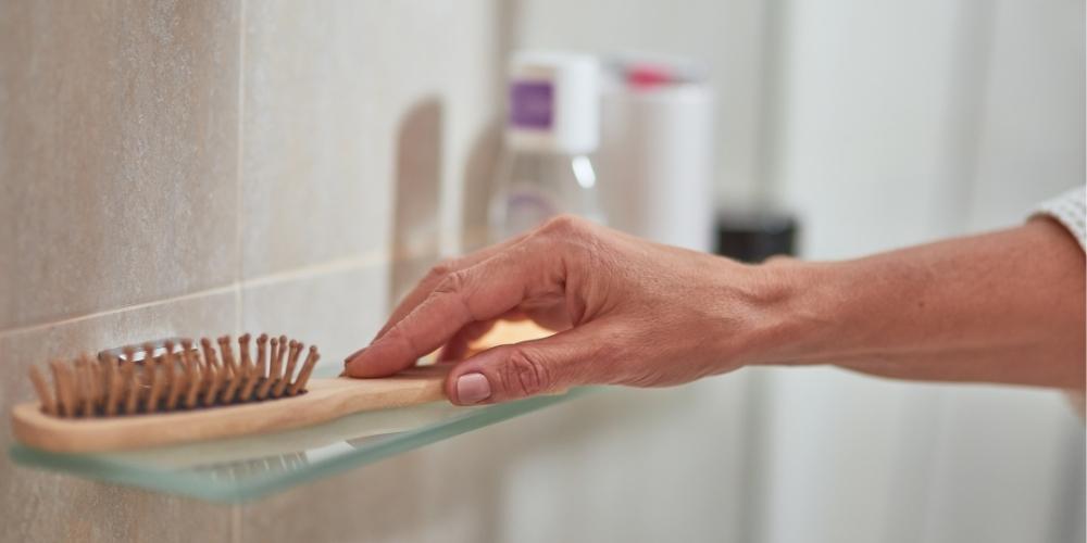 hand taking wooden hair brush