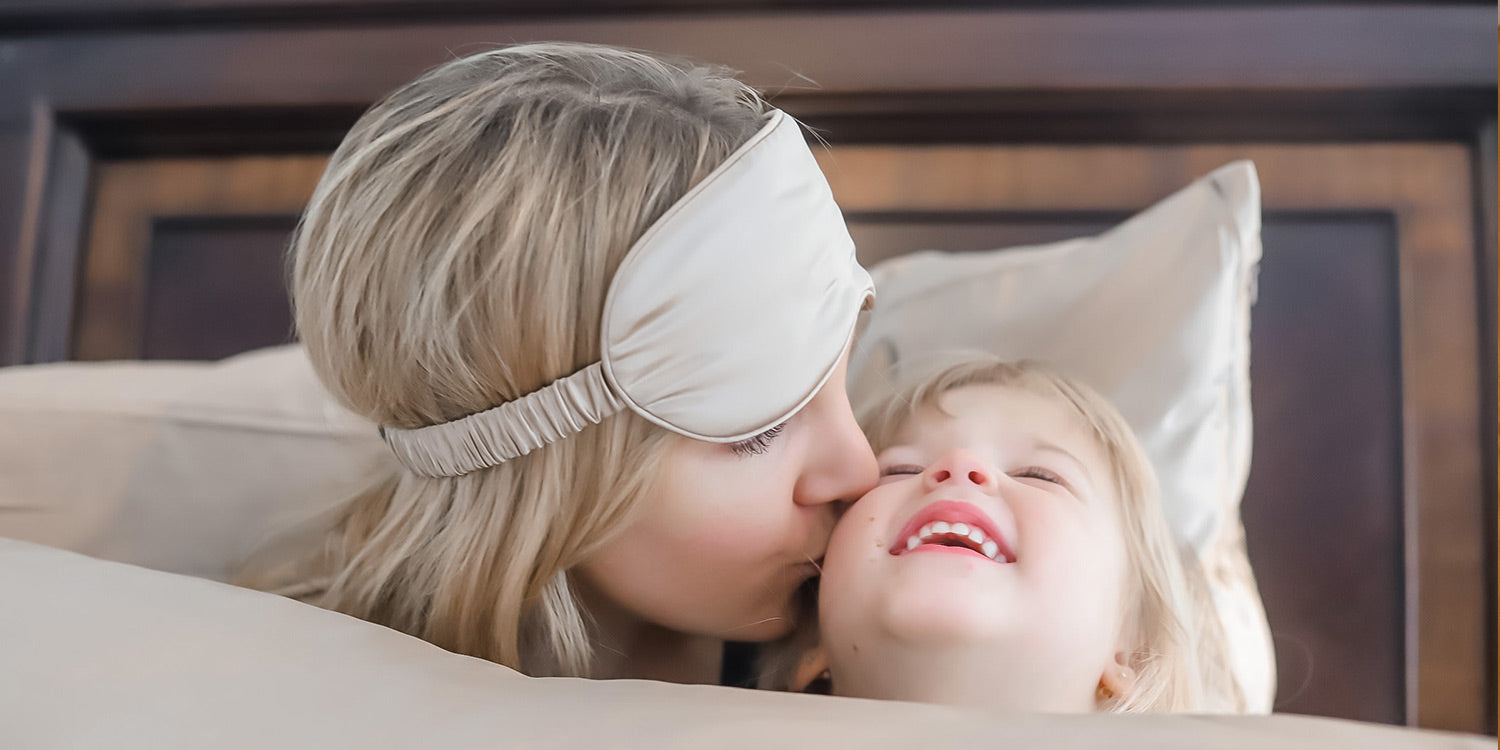 mother kissing baby with white Blissy silk pillowcase and sleep mask mother's day special gift