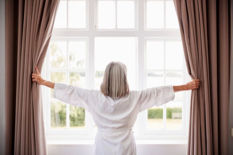 woman opening thick curtains