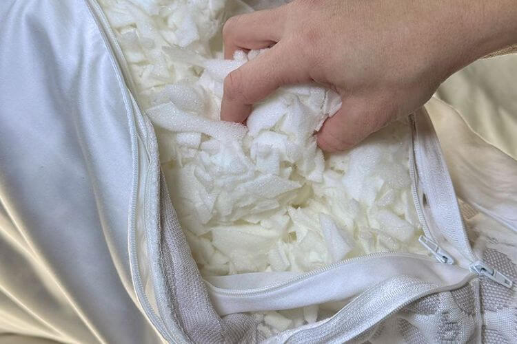 Hand adjusting removable layers of shredded memory foam inside a quality bed pillow with breathable outer cover