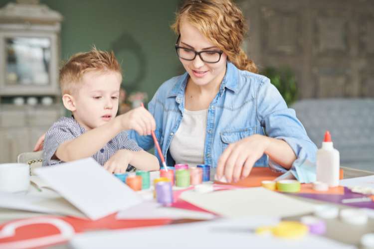 teacher helping cute little boy with art project