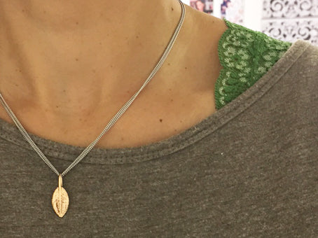 Yellow gold feather of friendship pendant charm styled on a sterling silver chain